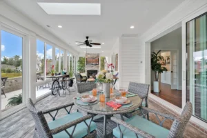 Bright modern sunroom with wicker dining set, turquoise cushions, and panoramic natural light views.
