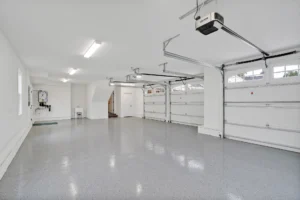 Bright three-car garage with glossy epoxy floor, white walls, and modern automatic doors.
