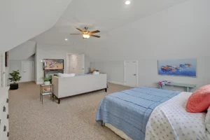 Bright attic bedroom with soft gray walls, cozy sofa, light blue bedding, and modern décor.