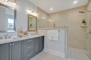 Modern gray vanity bathroom with white countertop and glass walk-in shower in neutral tones.