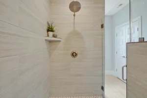 Minimalist beige-tiled walk-in shower with rainfall showerhead and green plants for modern bathroom style.