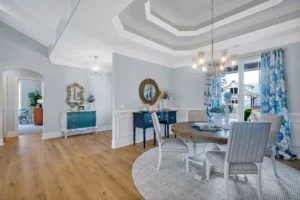 Elegant coastal dining room with soft blue tones, modern chandelier, and bright open-concept design.