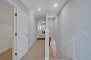 Modern gray upstairs hallway with beige carpet, white trim, recessed lighting, and contemporary design.