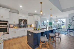Modern navy and white kitchen with gold accents, rattan stools, and marble island countertop.