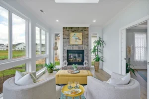 Bright airy living room with brick fireplace, blue walls, wood floors, and natural light.