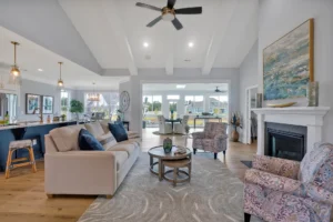 Bright modern farmhouse living room with beige sectional, glass coffee table, and open kitchen.