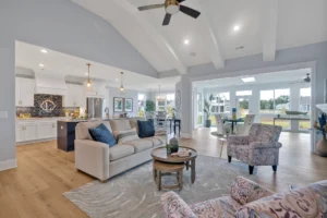 Spacious modern open-concept living room with vaulted ceilings, white beams, and bright natural light.