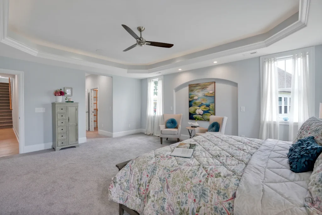 Elegant modern bedroom with floral bedding, cozy sitting area, and soft natural lighting.
