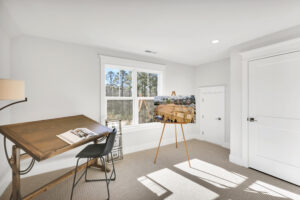 Bright modern art studio with natural light, wooden desk, easel, and serene creative atmosphere.