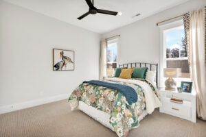 Bright modern bedroom with floral bedding, natural light, and elegant neutral décor.
