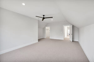 Bright modern loft bedroom with white walls, beige carpet, and black ceiling fan.