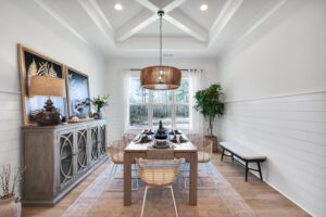 Modern farmhouse dining room with wooden table, rattan chairs, and warm coastal rustic decor.