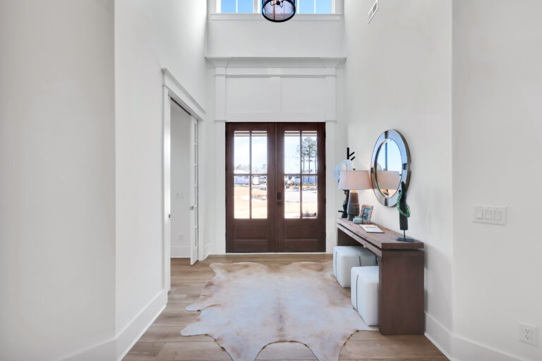 Modern farmhouse entryway with wooden double doors, light floors, cowhide rug, and rustic decor.