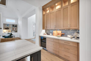 Modern light wood kitchen with blue subway tile backsplash and white marble island.