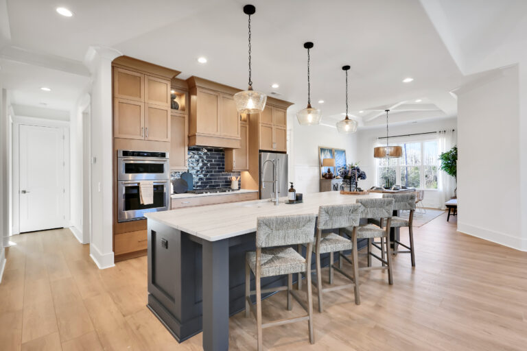 Bright modern kitchen with navy island, light wood cabinets, and stainless steel appliances.