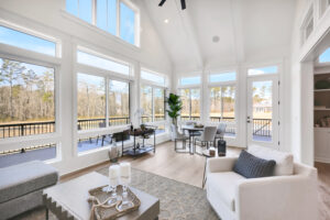 Bright contemporary coastal living room with floor-to-ceiling windows and serene water view.