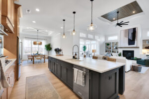 Bright modern open-concept kitchen and living room with island, wood accents, and cozy fireplace.
