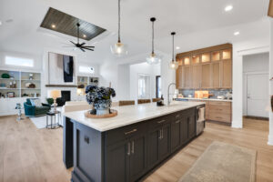 Bright modern kitchen and living room with marble island, wood cabinets, and cozy fireplace.
