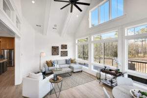 Bright modern living room with vaulted ceilings, gray sectional, and floor-to-ceiling windows.