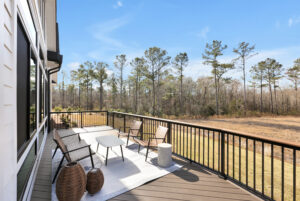 Modern outdoor deck with cozy seating, wood flooring, and scenic forest view.