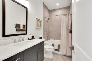 Modern neutral bathroom with marble vanity, dual sinks, beige tile, and brushed nickel fixtures.