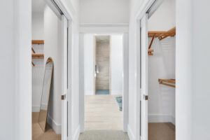 Bright modern hallway with dual walk-in closets leading to a stylish contemporary bathroom.