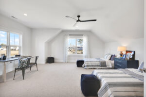 Bright modern twin bedroom with neutral decor, striped bedding, and ample natural light.